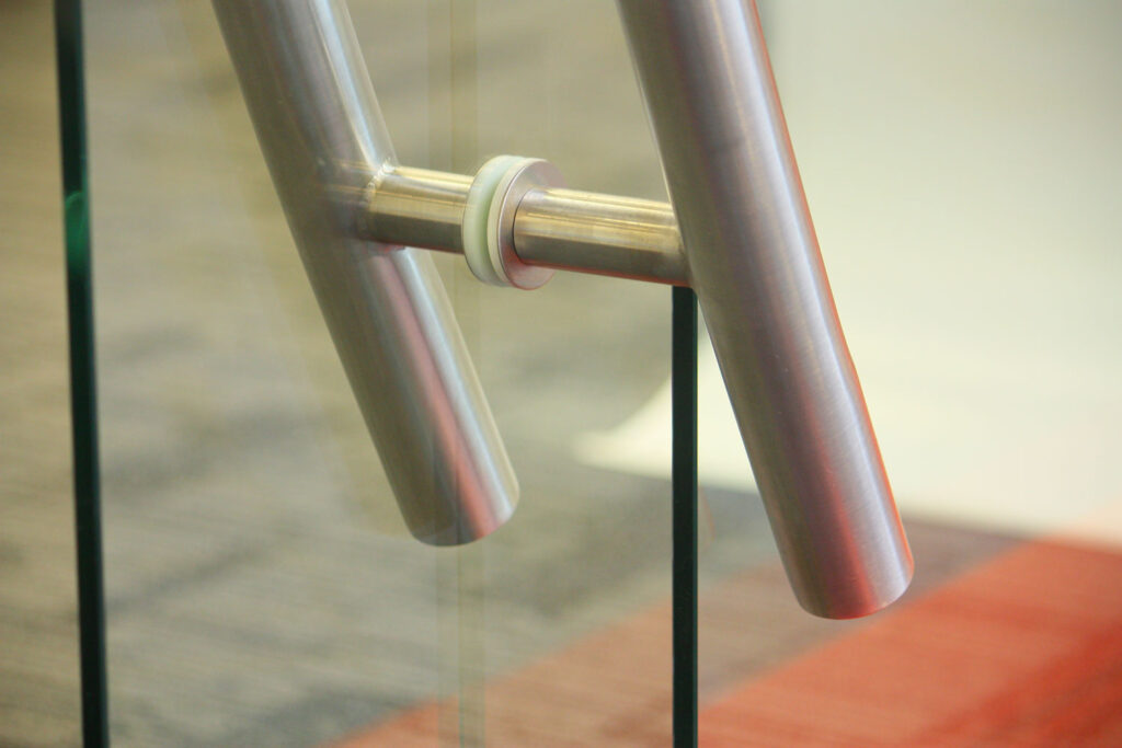 Detail spojení nerezového madla na skleněných dveřích